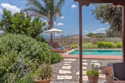 a backyard with a swimming pool and an umbrella at Yiannis Cottage in Spiliá