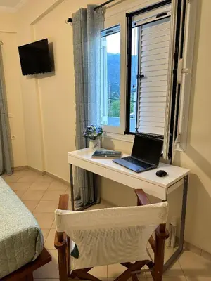 a desk with a laptop on it in a room with a window at Glikanisos House Nipos - ideal for hikers and families 2bd, 6pl, 10min to beach in Nípos