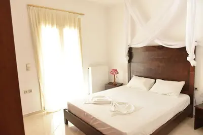 a bedroom with a large white bed with a wooden headboard at apartment irini in Vryses