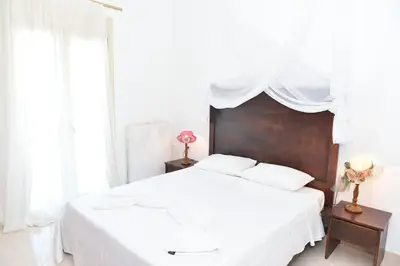 a white bedroom with a large bed with a wooden headboard at apartment irini in Vryses
