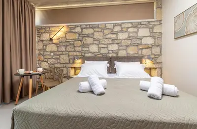 a bedroom with a stone wall and a bed with pillows at Achatis Apartments with sea view in Kolymvari