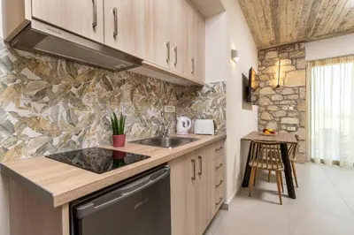 a kitchen with a sink and a stone wall at Achatis Apartments with sea view in Kolymvari