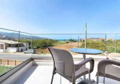 a balcony with a table and chairs and a view of the ocean at Achatis Apartments with sea view in Kolymvari