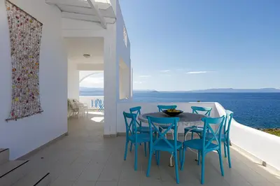 a dining room with a table and chairs and the ocean at Villa Chryssi in Tersanas