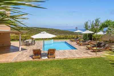 a swimming pool with lounge chairs and umbrellas at Villa Ariella With Sea View in Agia Marina Nea Kydonias