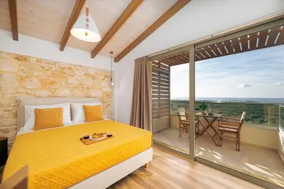 a bedroom with a bed and a balcony with a table at Athali Luxury Pocket Villa Stunning Sea View in Falasarna