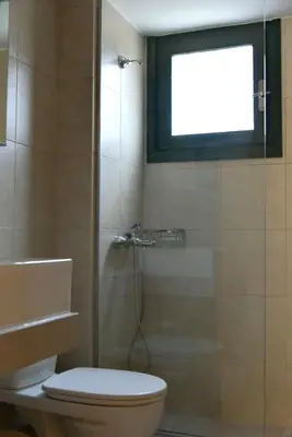 a bathroom with a toilet and a shower with a window at Madrugada in Chania Town