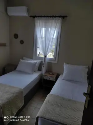a bedroom with two beds and a window with curtains at Olives Villa in Anopoli Sfakion