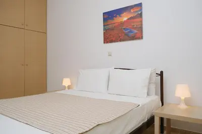 a bedroom with a bed with white sheets and two lamps at AVRA COZY APARTMENT Agioi Apostoloi Chania in Daratso