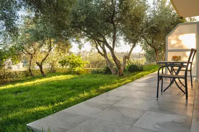 a patio with a table and chairs and a lawn at AVRA COZY APARTMENT Agioi Apostoloi Chania in Daratso