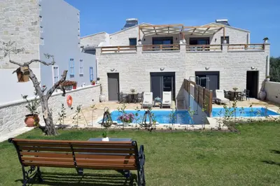 a bench in front of a house with a pool at Sun Flower Villas in Agia Marina Nea Kydonias