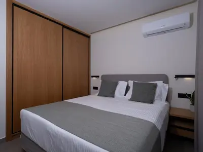 a bedroom with a large white bed with wooden cabinets at Mossa Concept Villas - heated pool- 200 m from the beach in Daratso