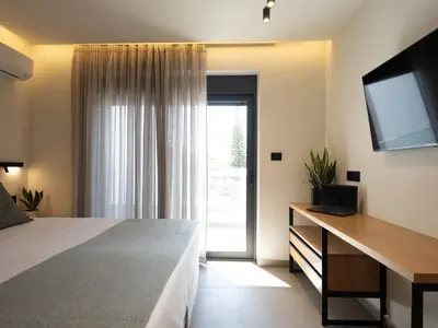 a bedroom with a bed and a desk with a television at Mossa Concept Villas - heated pool- 200 m from the beach in Daratso