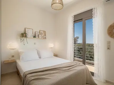 a white bedroom with a bed and a balcony at Sol Luxury Apartment - close to the beach with a private heated mini pool in Chania Town