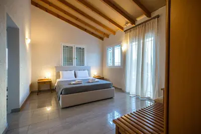 a bedroom with a bed in a room with windows at Zoe's Place - 1 BD Loft Beachfront Apartment in Kissamos