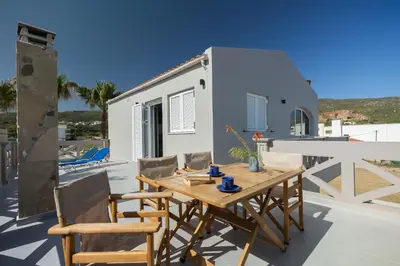 a table and chairs on a patio with a house at Zoe's Place - 1 BD Loft Beachfront Apartment in Kissamos