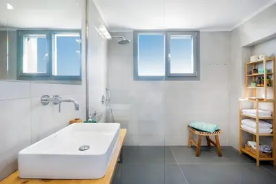 a bathroom with a white sink and a shower at Sea Apt - Akrotiri in Kounoupidhianá