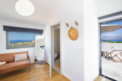 a living room with a couch and a large window at Sea Apt - Akrotiri in Kounoupidhianá