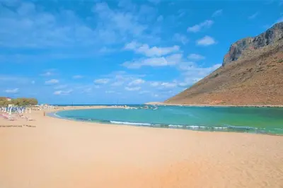 a beach with people sitting on the sand and the water at Olive Apt - Akrotiri in Kounoupidhianá