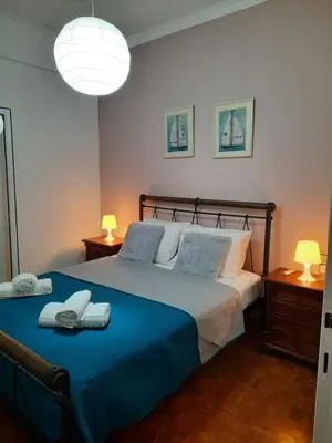 a bedroom with a bed with blue sheets and two lamps at Apartment Chania - Nea Chora in Chania Town
