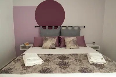 a bedroom with a large bed with a purple headboard at Michael Apartments 2 in Agia Marina Nea Kydonias