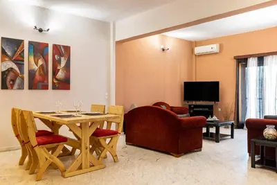 a living room with a table and chairs and a television at Big spacious apartment in the heart of the city! in Chania Town