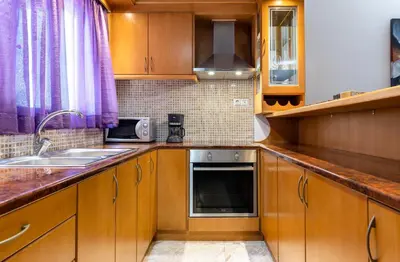 a kitchen with wooden cabinets and a sink and a microwave at Big spacious apartment in the heart of the city! in Chania Town