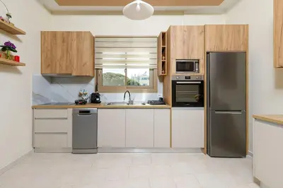 a kitchen with white cabinets and a stainless steel refrigerator at TziApartment in downtown Chania in Chania Town