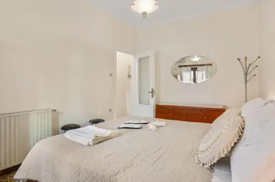 a white bedroom with a large bed with a mirror at Sunset Apartment in Platanias in Plataniás