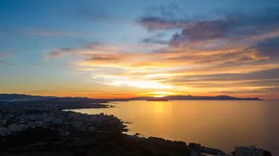 a sunset over the water with a city and the ocean at Dreta Suites in Chania Town