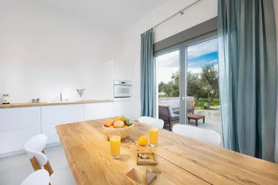 a kitchen with a wooden table with a bowl of fruit at Olisea Villa, olive grove seaview villa in Kounoupidhianá