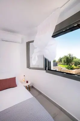 a bedroom with a white bed and a window at Olisea Villa, olive grove seaview villa in Kounoupidhianá