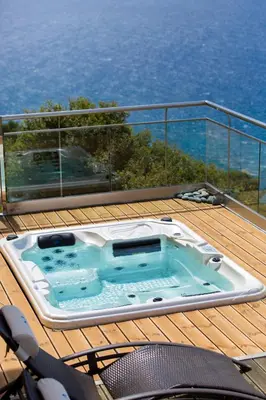 a hot tub on the deck of a house at Eleni's Serenity - Discovering Sapphire Harmonies in Ravdhoúkha