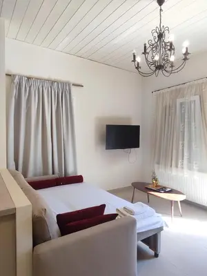a bedroom with a bed and a couch and a tv at The Gem Of Talos Apartment in Stalos