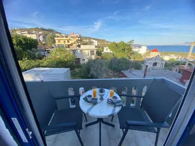 a table and chairs on a balcony with a view at Rouan Studios in Souda