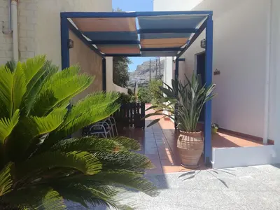 a patio with plants and a blue door with a balcony at Lissos Studios - Rooms in Palaiochóra