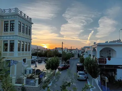 a city street at sunset with cars parked on the street at Lissos Studios - Rooms in Palaiochóra