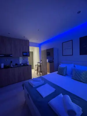 a blue room with a large bed and a kitchen at Rouan studios 1 in Souda
