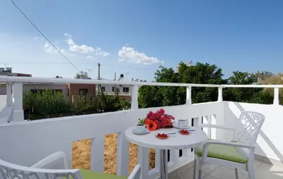 a white table and chairs on a balcony at Studios George in Palaiochóra