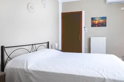 a bedroom with a white bed and a brown door at Kaliopi's Apartments in Chania Town