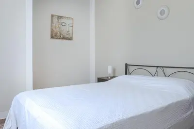 a white bed in a white bedroom with a picture on the wall at Kaliopi's Apartments in Chania Town