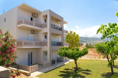 a white building with trees in front of it at Kalami Apartments in Falasarna