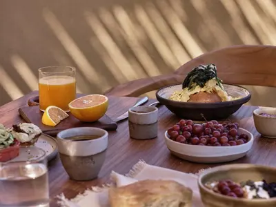 a wooden table topped with plates of food and orange juice at Tella Thera, a Member of Design Hotels in Kissamos
