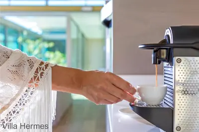 a person pouring a cup of coffee into a coffee machine at Elafonisi Villas in Livadia