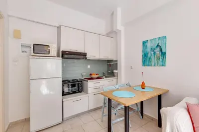 a kitchen with a table and a white refrigerator at Backyard Art Studio in Chania Town