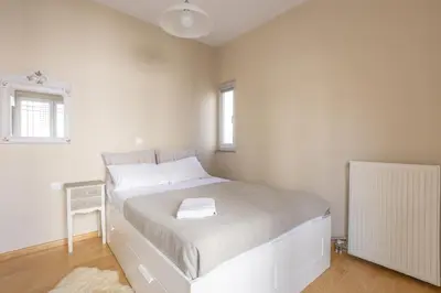 a white bedroom with a bed and a window at Cozy Apartment 50m to beach, 5min walk to Old Town in Chania Town