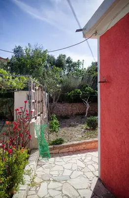 a yard with a red wall and a garden at Levendi's House in Kissamos