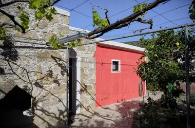 a red door on the side of a stone building at Levendi's House in Kissamos