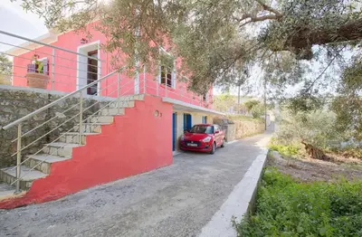 a red car parked in front of a red building at Levendi's House in Kissamos