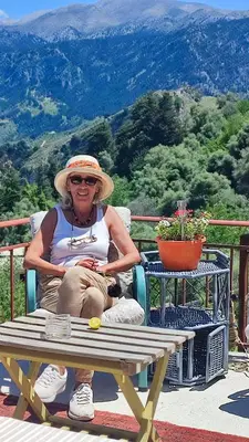 a woman sitting in a chair at a picnic table at Η αυλή της Ασπασίας, Χανιά Κρήτη in Lákkoi